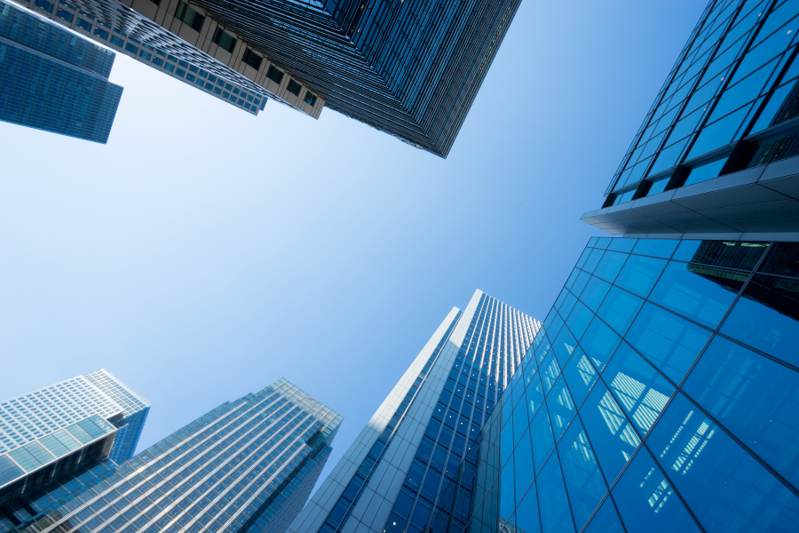 Edifícios corporativos e arranha-céus modernos vistos de baixo para cima contra um céu limpo, simbolizando investimento empresarial e financiamento para negócios.